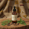 African herbal hair oil blend bottle surrounded by moringa, neem, chebe and black seeds