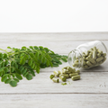 Organic Moringa Capsules in glass bottle with moringa leaves